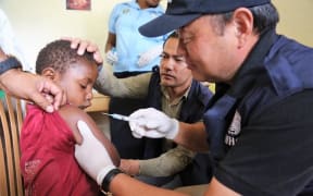WHO Representative Dr Luo Dapeng administering the measles-rubella vaccine to a child in Jiwaka province.