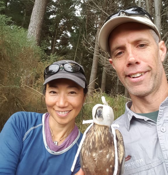 Falcon researchers Chifuyu Horikoshi and Graham Parker. The falcon's head is covered in a helmet to keep it calm while it is being handled.