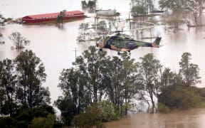 This handout photo taken on 28 February, 2022, and received on 1 March, 2022, from the Australian Defence Force (ADF) shows an Australian Army MRH90 Taipan helicopter from the School of Army Aviation flying over flood-affected properties in the Ballina region of New South Wales.