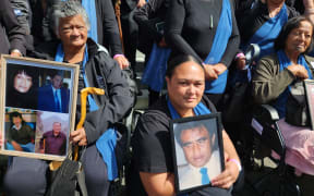 Whānau on the steps of Parliament with photos of their loved ones.
