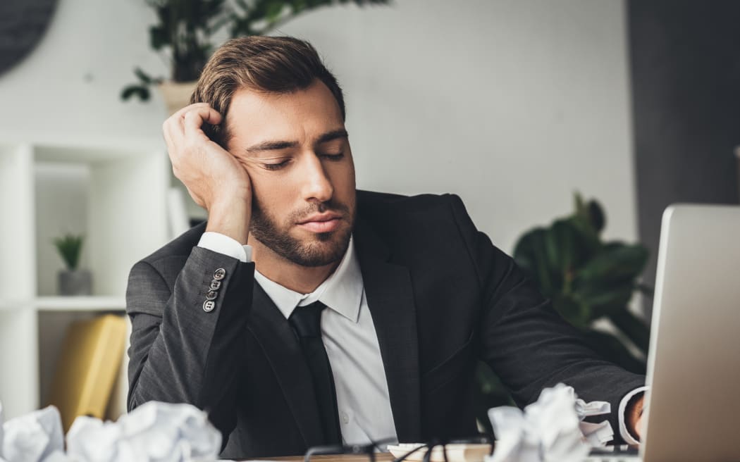 sleeping overworked businessman with crumpled papers on desk