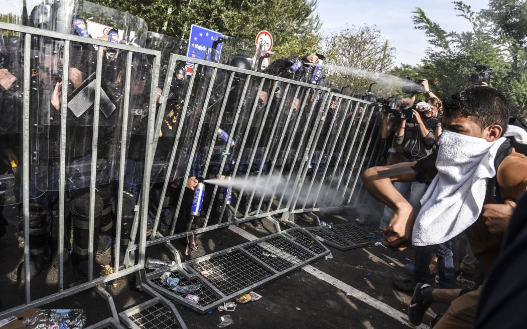Hungarian riot police use pepper spray to push back refugees at the Hungarian border with Serbia.