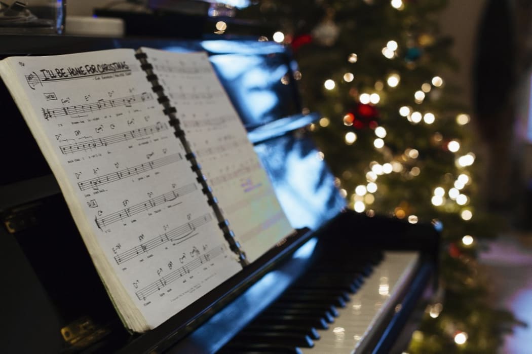 Sheet music on piano, Christmas tree in background (Photo by Adam C Bartlett / Image Source / Image Source via AFP)