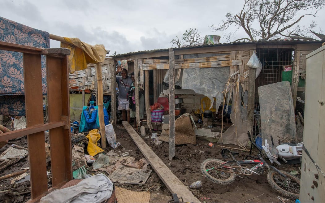 Residents in the remains of their cyclone-damaged home.