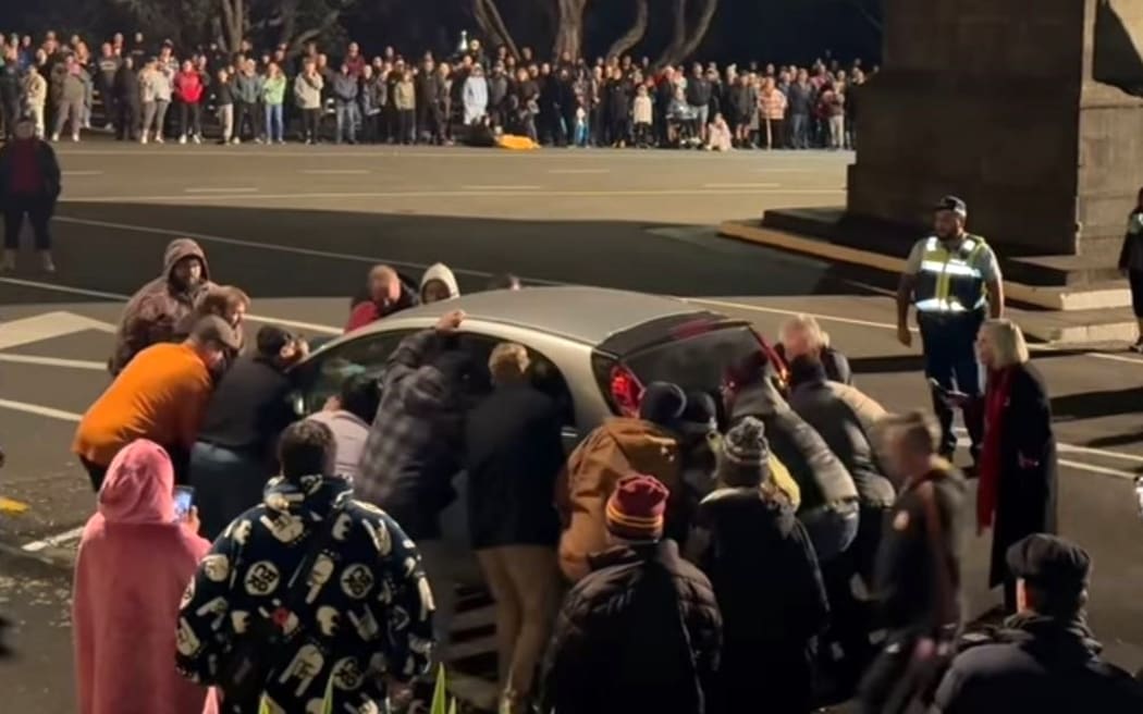 Attendees at New Plymouth's 2024 Anzac Day service lift a car blocking the view.