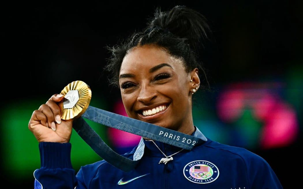 US' Simone Biles poses with her gold medal during the podium ceremony after the artistic gymnastics women's all around final during the Paris 2024 Olympic Games at the Bercy Arena in Paris, on August 1, 2024. (Photo by Loic VENANCE / AFP)