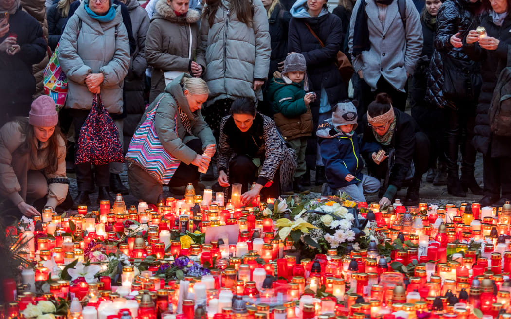 Well wishers light candles as people mourn at a makeshift memorial for the victims outside the Charles University in central Prague, on December 22, 2023, as police investigators kept working on the campus the day after a deadly mass shooting. The gunman who opened fire at Prague's Charles University killed 13 people and then himself, Czech authorities said, revising the toll from 14 victims. Czech authorities sought a motive in the a student's gun attack at the Charles University's Faculty of Arts. The gunman, a 24-year-old student, died during the attack on December 21, 2023. (Photo by Radek Mica / AFP)