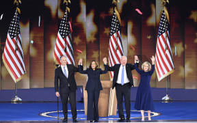 US Vice President and Democratic presidential candidate Kamala Harris (2L) stands onstage with Second Gentleman Douglas Emhoff, Minnesota Governor and Democratic vice presidential candidate Tim Walz and Gwen Walz on the fourth and last day of the Democratic National Convention (DNC) at the United Center in Chicago, Illinois, on August 22, 2024. Vice President Kamala Harris will formally accept the party’s nomination for president today at the DNC which ran from August 19-22 in Chicago. (Photo by Mandel NGAN / AFP)