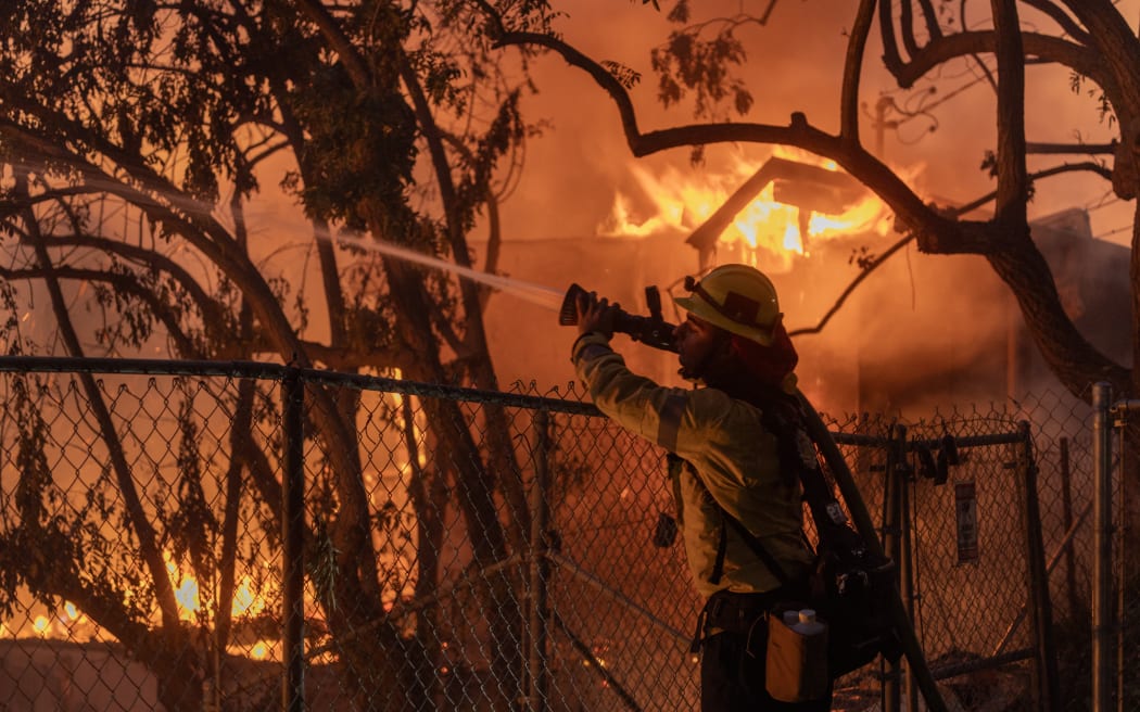 Los Angeles County firefighter battles flames as a home burns from the Mountain Fire on 6 November 2024 in Camarillo, California.
