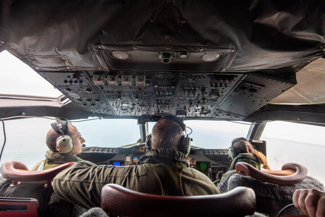A P-3K2 Orion aircraft flies over an area of Tonga that shows the heavy ash fall from the recent volcanic eruption within the Tongan Islands.