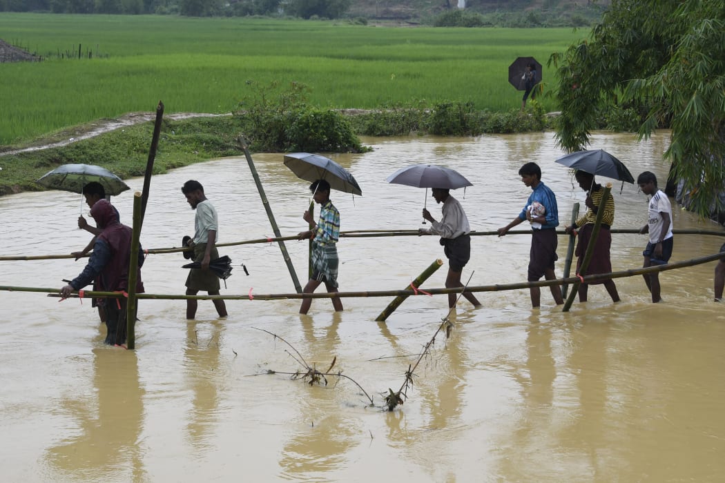 Rohingya Muslim refugees cross floodwater in Thyangkhali refugee camp near the Bangladesh town of Ukhia on September 17, 2017.