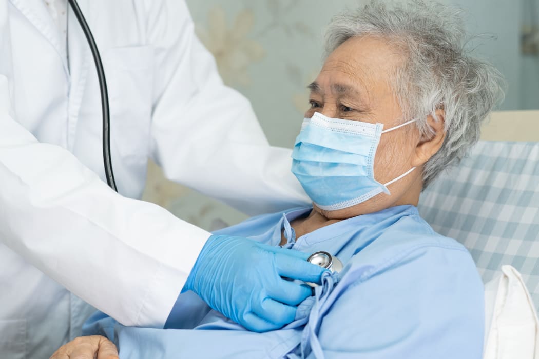 A patient wearing a face mask being checked on by a doctor in hospital, during the Covid-19 pandemic.