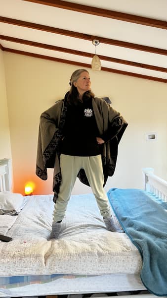 Penelope Brown striking a Wonder Woman pose on her bed.