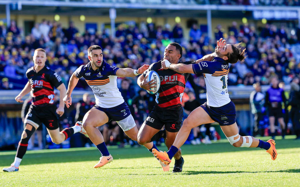 Sevu Reece palms off Andy Muirhead during the Super Rugby Pacific match between ACT Brumbies v Crusaders, GIO Stadium Canberra.