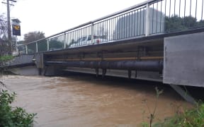 Don Buck Road bridge overflowing in West Auckland.