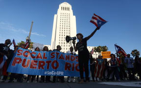 Protestors rally before a candlelight vigil outside City Hall, while demanding the resignation of Ricardo Rossello, the Governor of Puerto Rico.