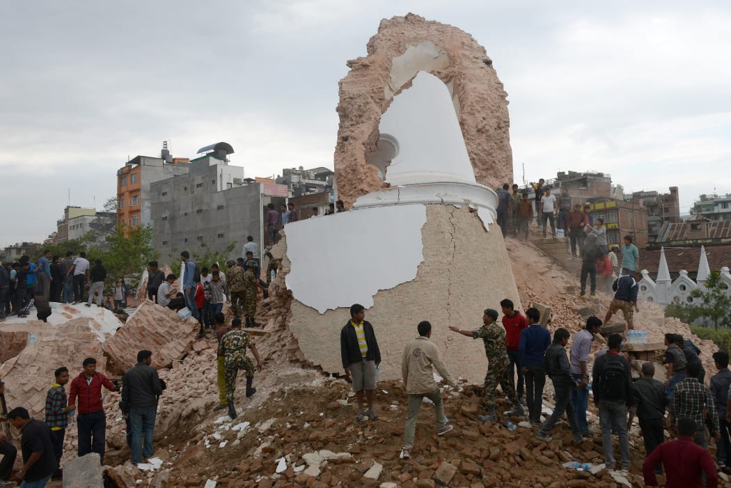 Onlookers and rescue workers gather at the foot of the destroyed Darahara Tower.