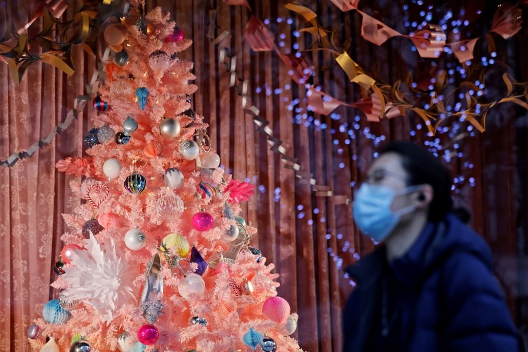 A pedestrian wearing a face mask or covering due to the COVID-19 pandemic, walks past a Christmas-themed display in a shop window on Oxford Street in central London on December 22, 2020.