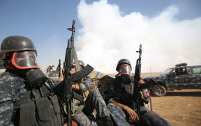 Iraqi forces wear gas as smoke billows from a burning sulphur factory about 30km south of Mosul.