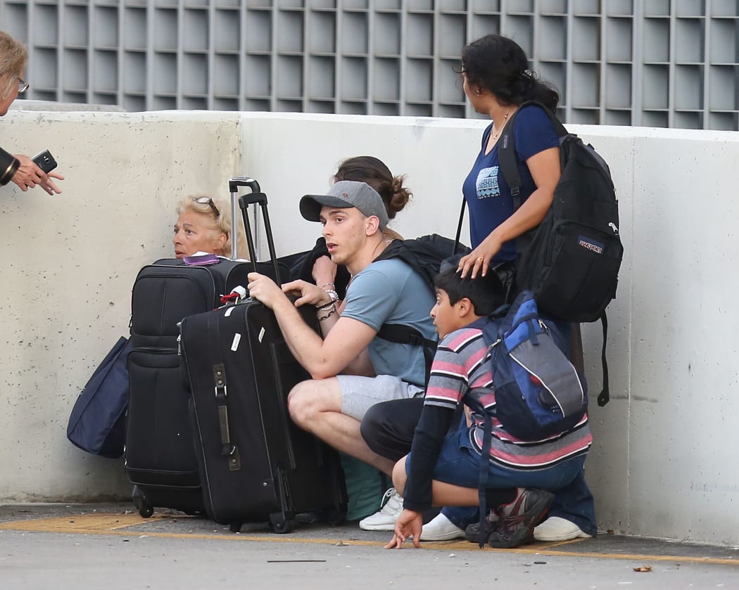 Passengers take cover as first responders secure the area outside the Fort Lauderdale-Hollywood International airport.