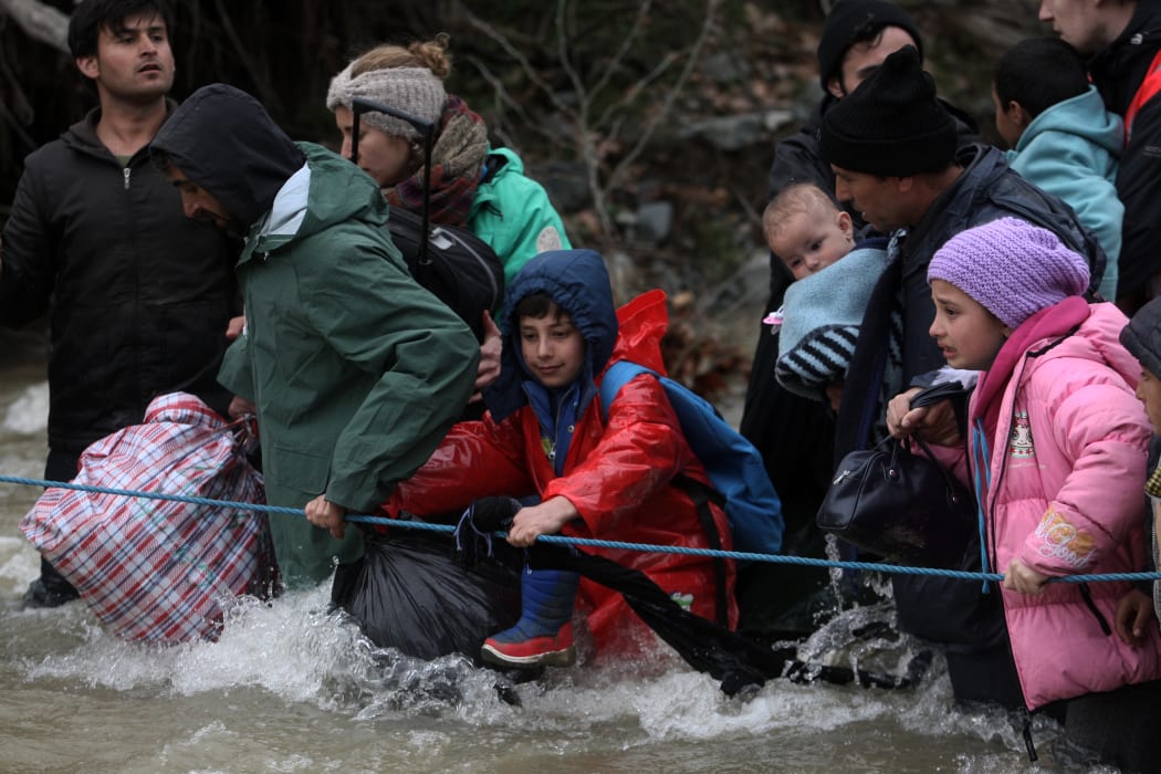 Refugees cross a river on their way to Macedonia from a makeshift camp at the Greek-Macedonian border.