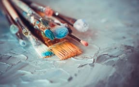 Paintbrushes on artist canvas covered  with oil paints