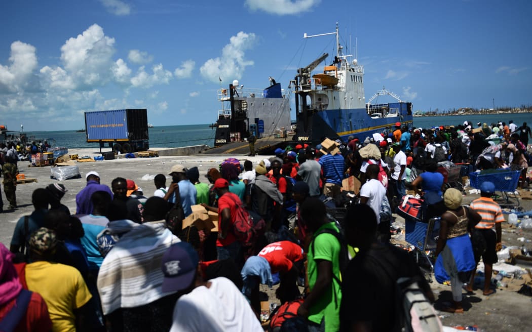 People wait to board a cargo ship for evacuation to Nassau at the port after Hurricane Dorian September 7, 2019, in Marsh Harbor, Great Abaco.