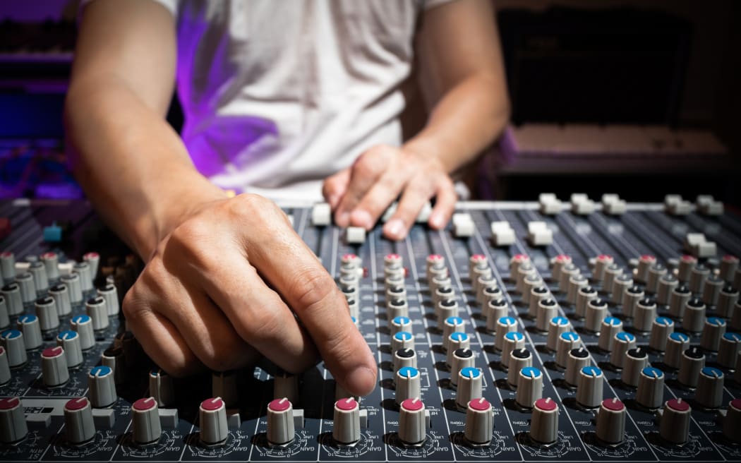 Sound engineer hand adjusting eq knobs on audio mixing console. recording and broadcasting concept.