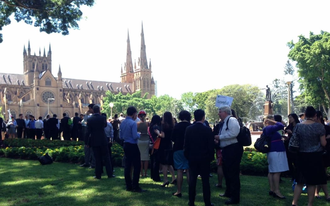 Evacuees in Hyde Park, Sydney. Hostages are being held at a chocolate cafe in Sydney's central business district, surrounded by police.