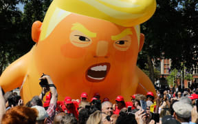 Activists inflate a giant balloon depicting US President Donald Trump as an orange baby during a demonstration against Trump's visit to the UK in Parliament Square in London.