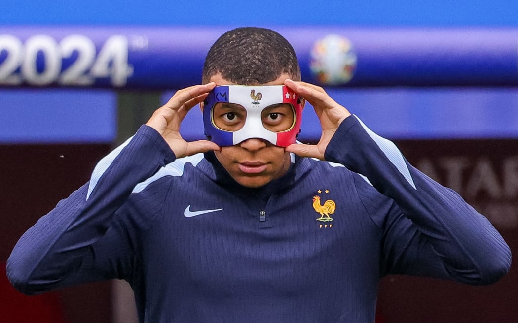 France's Kylian Mbappe tries on a protective mask.