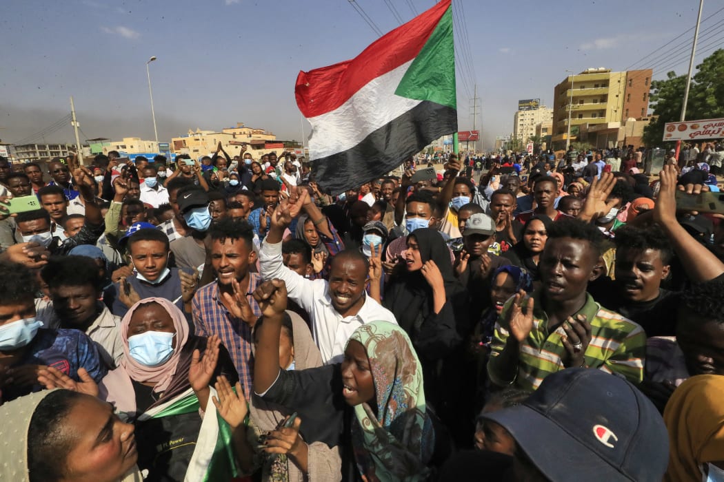 Sudanese protesters lift national flags as they rally on 60th Street in the capital Khartoum, to denounce overnight detentions by the army of government members.