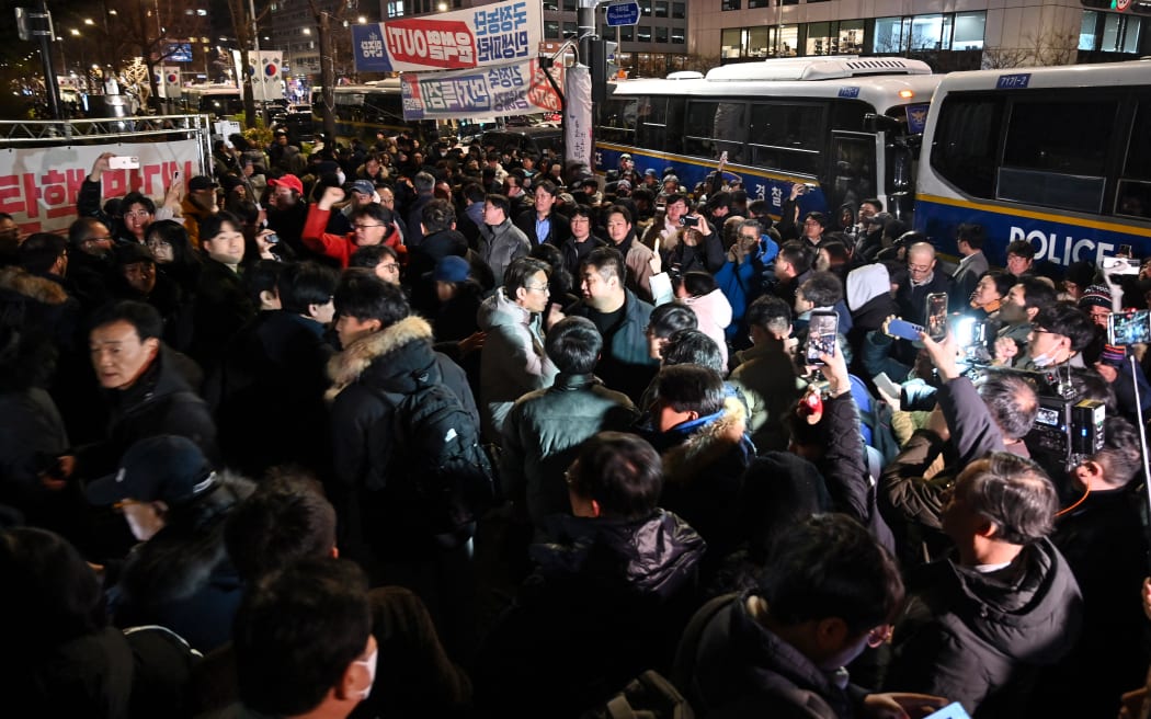 People gather in front of the main gate of the National Assembly in Seoul, South Korea on December 4, 2024, after President Yoon Suk Yeol declared emergency martial law. - South Korea's President Yoon Suk Yeol on December 3 declared emergency martial law, saying the step was necessary to protect the country from "communist forces" amid parliamentary wrangling over a budget bill. (Photo by JUNG YEON-JE / AFP)
