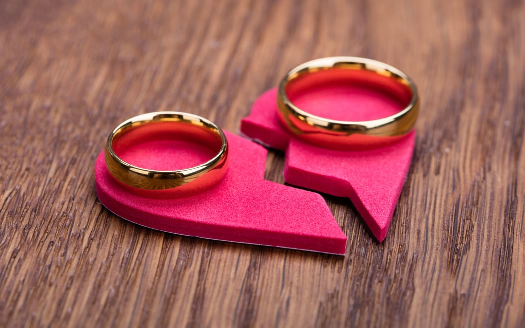 69590501 - high angle view of golden ring on red broken heart at wooden desk