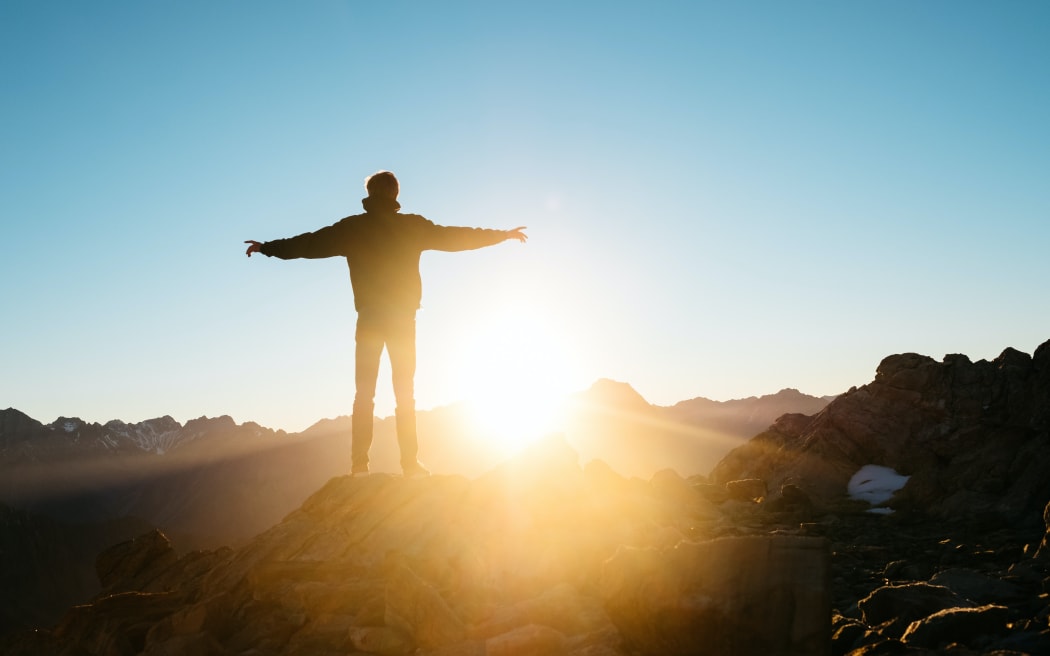 Man standing in New Zealand mountains at sunrise