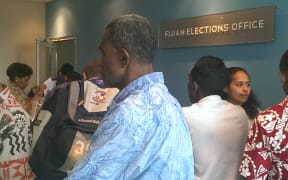 Crowd of polling workers at elections office after pages of names of people needed to work published in morning paper