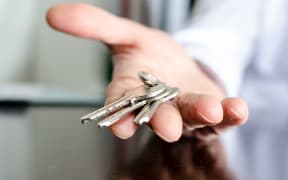 Estate agent showing house keys on a wooden table