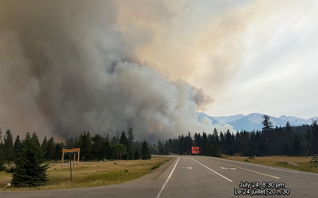 In this July 24, 2024, image obtained from the Jasper National Park in Canada, smoke rises from a wildfire burning in the park. The "out of control" wildfire has devoured up to half of the main town in western Canada's popular Jasper National Park, authorities said July 25, with 400 foreign firefighters called in to help battle the blaze. (Photo by Handout / Jasper National Park / AFP)