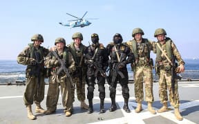 A handout photo made available by the Iranian Army office on February 17, 2021, shows Iranian Revolutionary Guards Corps (IRGC) and Russian soldiers taking part in a drill simulating taking over a hijacked ship, during joint naval drills between Iran and Russia in the northern Indian Ocean. (Photo by Iranian Army office / AFP) / === RESTRICTED TO EDITORIAL USE - MANDATORY CREDIT "AFP PHOTO / HO / IRANIAN ARMY OFFICE" - NO MARKETING NO ADVERTISING CAMPAIGNS - DISTRIBUTED AS A SERVICE TO CLIENTS ===
