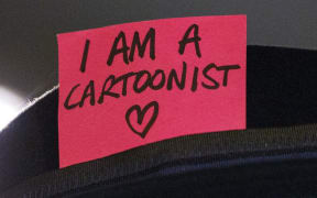 A cartoonist attends a silent vigil in Trafalgar Square, London.
