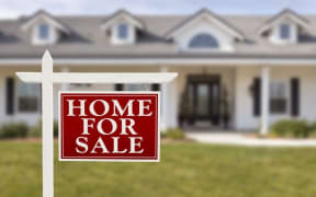 A house for sale sign outside a home (stock shot).