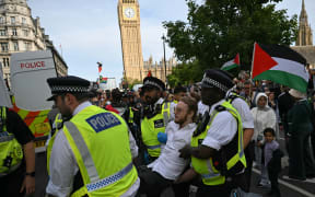 A protester is carried away by police officers at a "Lift The Ban" demonstration in support of the proscribed group Palestine Action, calling for the recently imposed ban to be lifted, in Parliament Square, central London, on September 6, 2025. (Photo by JUSTIN TALLIS / AFP)