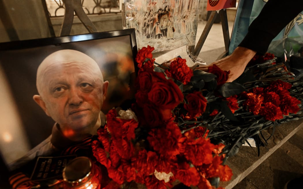 A man lays flowers at the makeshift memorial in honor of Yevgeny Prigozhin and Dmitry Utkin, who managed Wagner's operations and allegedly served in Russian military intelligence, in Moscow, on August 24, 2023.