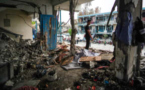 A Palestinian boy stands in a destroyed room a UN-school housing displaced people that was hit during Israeli bombardment in Nuseirat, in the central Gaza Strip, on 6 June, 2024.