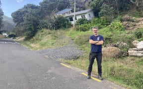 Toby stands at a slip on Karekare Road, one year on from the cyclone.