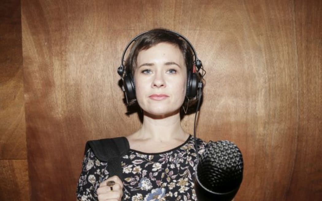 A portrait of Bang! presenter Melody Thomas, thrusting a microphone towards the camera.