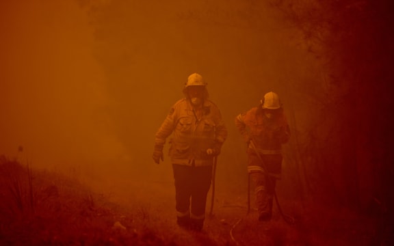Firefighters tackle a bushfire in thick smoke in the town of Moruya, south of Batemans Bay, in New South Wales on January 4, 2020.