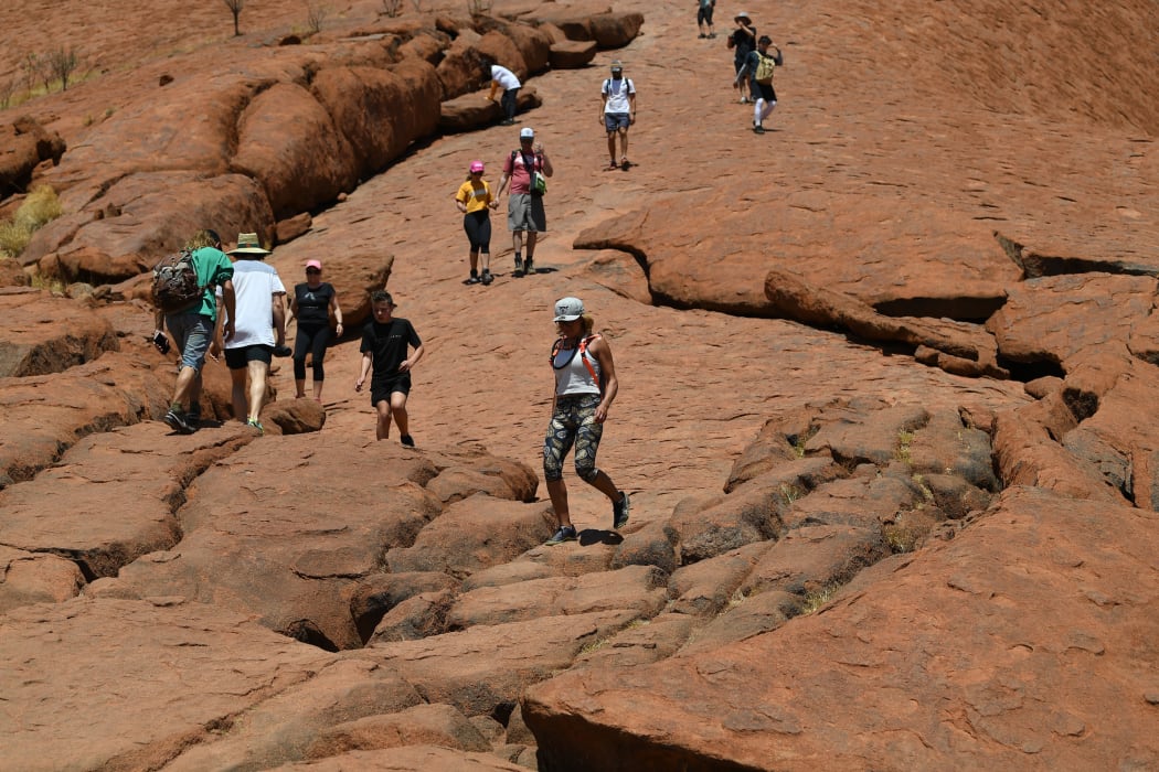 Tourists climb the Uluru, also known as Ayers Rock, on a sunny day at Uluru-Kata Tjuta National Park in Australia's Northern Territory on October 25, 2019. -