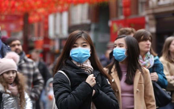 Women wear respirator masks during Chinese New Year Celebration in Chinatown in London, England on January 26, 2020.