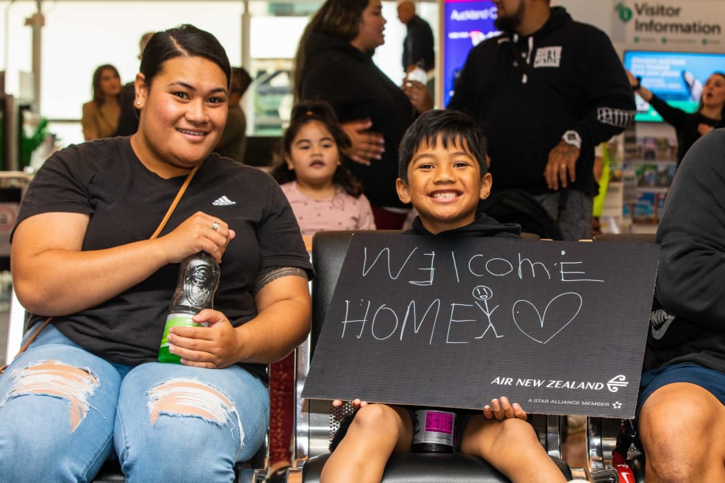 A boy holds a 'welcome home' sign as families wait for people on board the first flight from Sydney to Auckland under the trans-Tasman bubble arrangement.